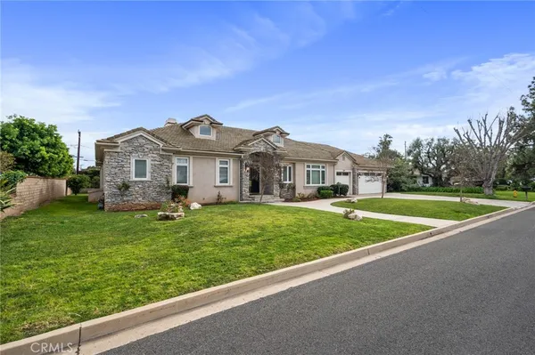 a view of house with a big yard and large trees