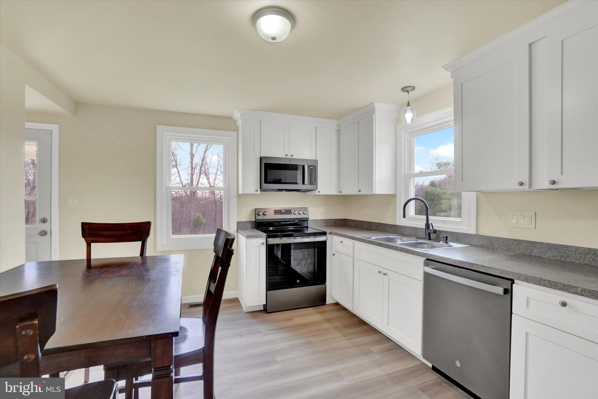 1050 Buck Road Dover, PA 17315 - Photo 6 of 28 a kitchen with stainless steel appliances granite countertop a stove a sink a microwave a dining table and chairs