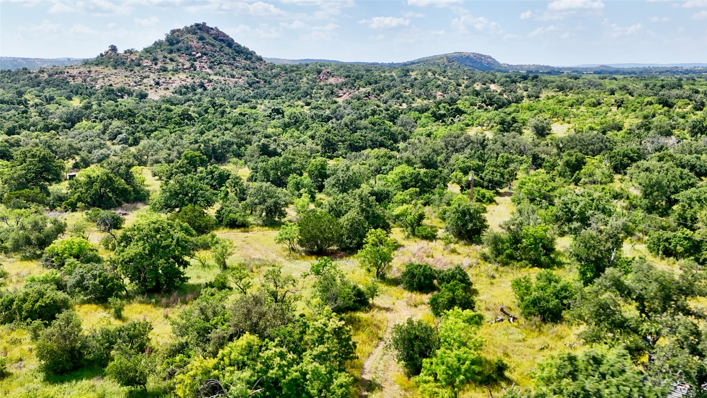 18248 Bode Peak Road Pontotoc, TX 76869 - Photo 2 of 17 Vast natural landscape showcasing abundant trees, open meadows, and distant hills under a bright sky.