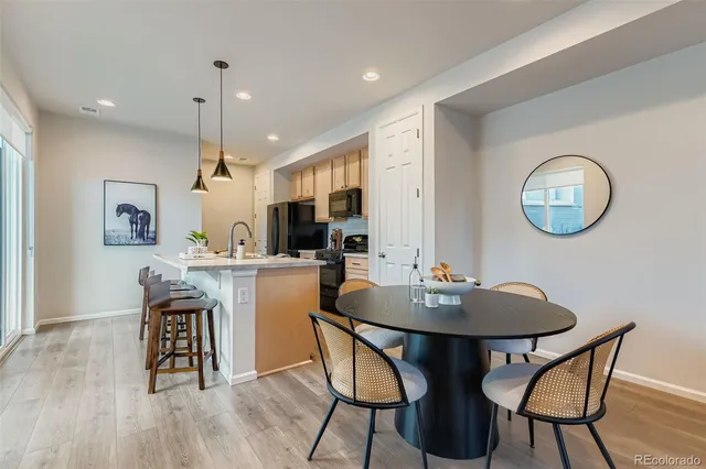 a kitchen with a dining table chairs and refrigerator