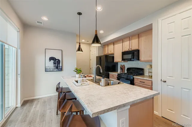 a kitchen that has a table chairs stainless steel appliances and wooden floor