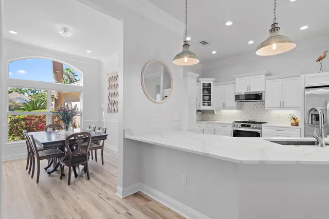 a kitchen with stainless steel appliances a dining table chairs and stove top oven