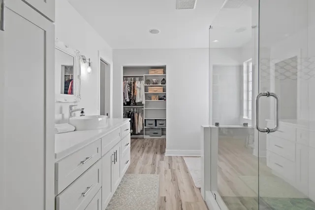 a spacious bathroom with a double vanity sink a mirror and shower