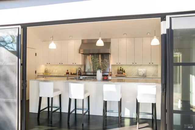 a kitchen with stainless steel appliances granite countertop a stove top oven a sink and white cabinets with wooden floor