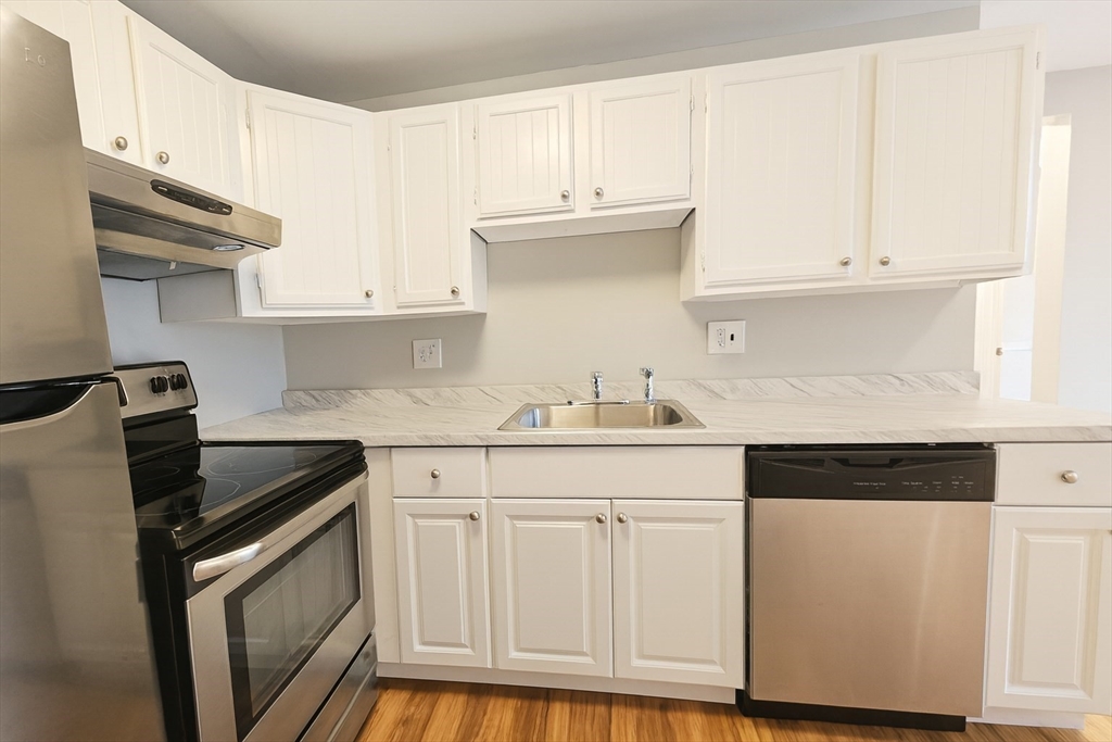 38 Carey Avenue, Unit 3 Watertown, MA 02472 - Photo 3 of 11 a kitchen with granite countertop white cabinets and black appliances