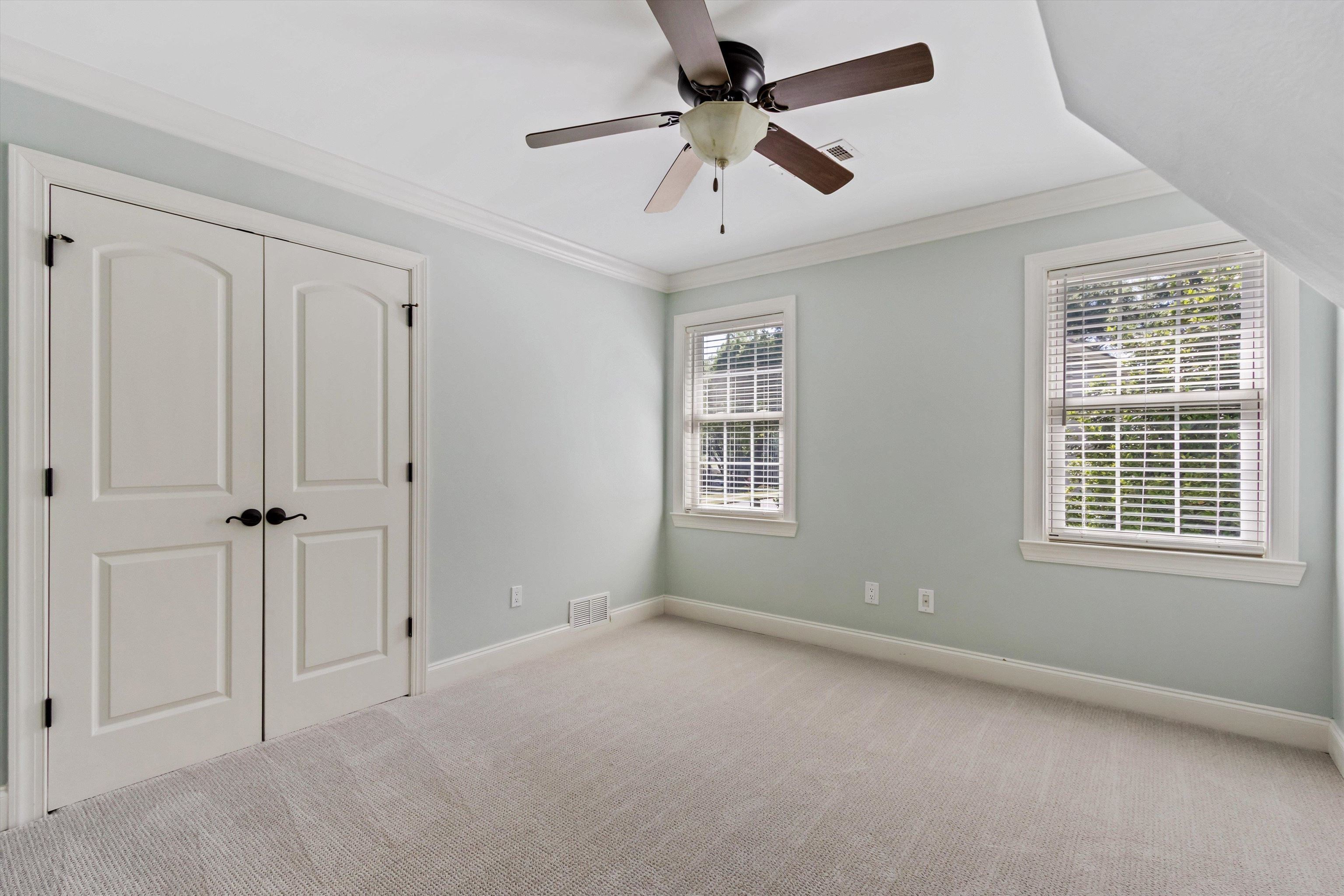 5302 South Angela Road Memphis, TN 38120 - Photo 29 of 40 Carpeted room featuring two arched panel doors with dark hardware, a ceiling fan with light fixture, and two double-hung windows with blinds