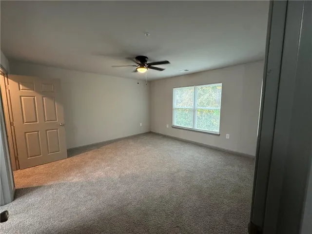 an empty room with windows and chandelier fan