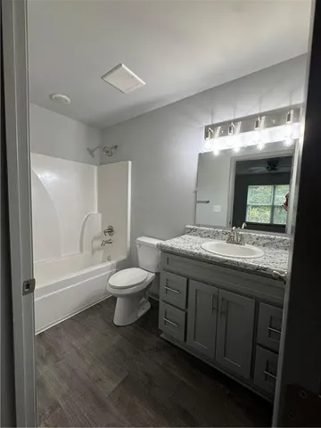 a bathroom with a granite countertop toilet a sink and a mirror