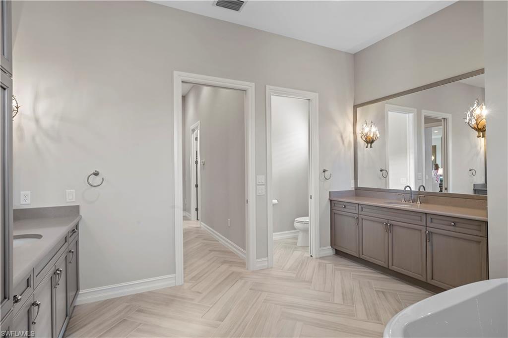 6254 Lightbourn Way Naples, FL 34113 - Photo 32 of 34 a spacious bathroom with a granite countertop sink a toilet a mirror and shower