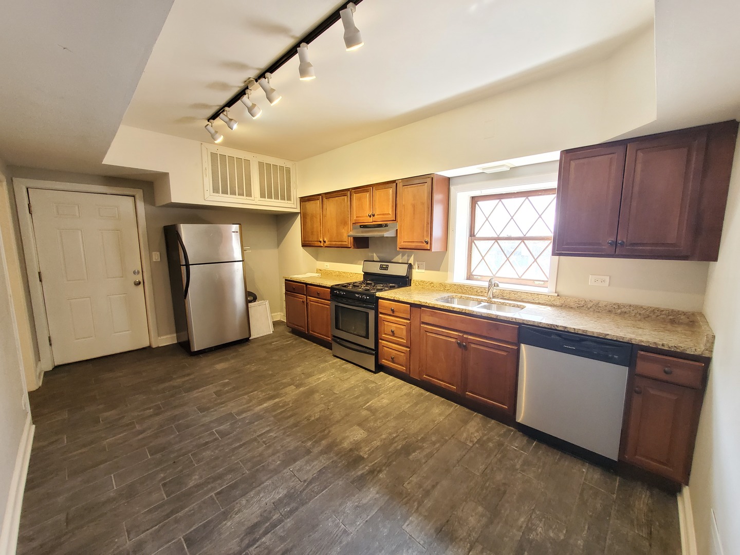 665 West Roscoe Street, Unit 1 Chicago, IL 60657 - Photo 6 of 10 a kitchen with granite countertop a sink cabinets stainless steel appliances and a window
