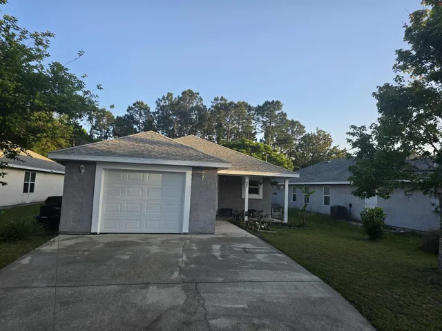a front view of house with yard and trees in the background