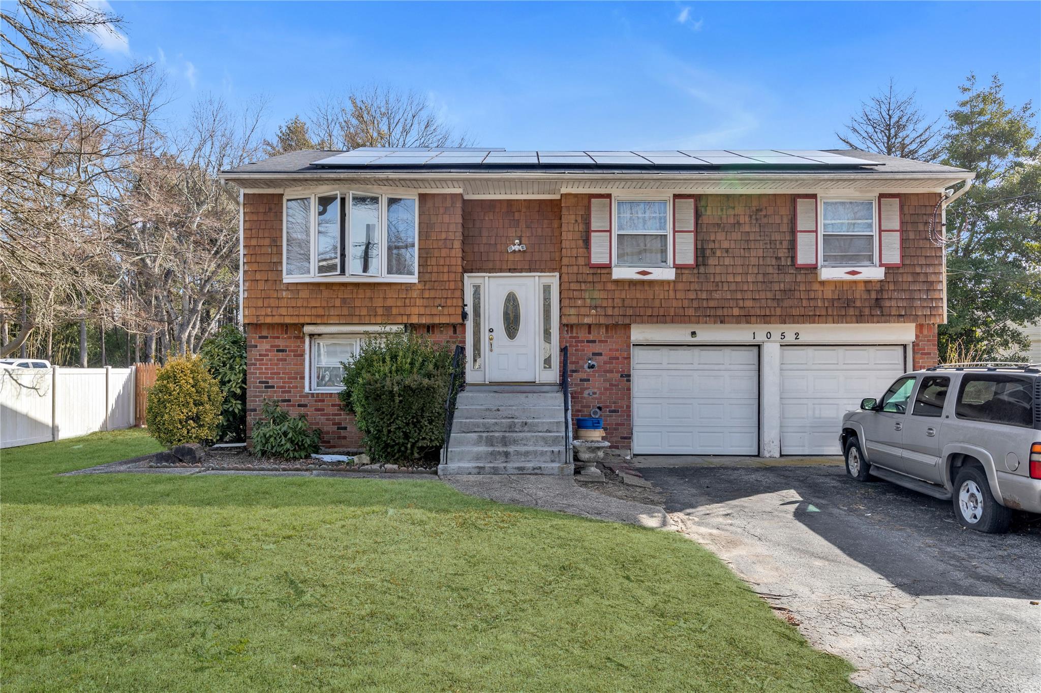 1052 Howells Road Bay Shore, NY 11706 - Photo 1 of 1 Raised ranch with solar panels, aphalt driveway, a front yard, and fence