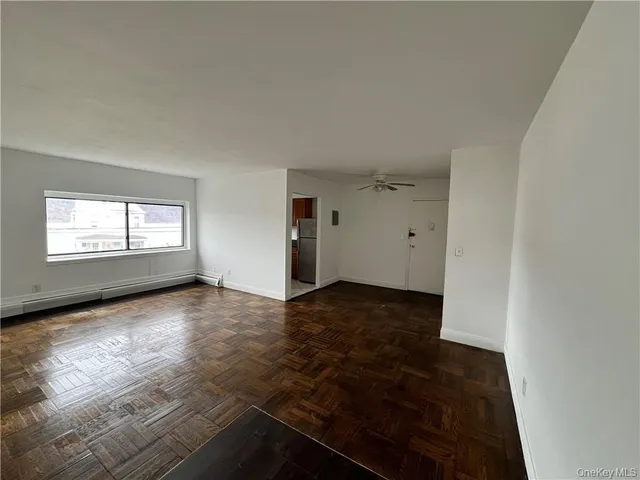 an empty room with wooden floor cabinet and windows