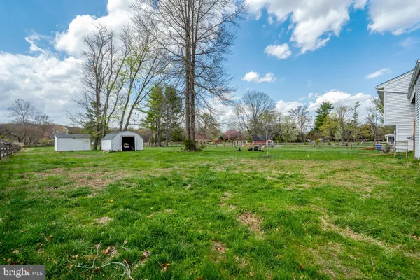 a view of backyard of house with wooden fence and large trees