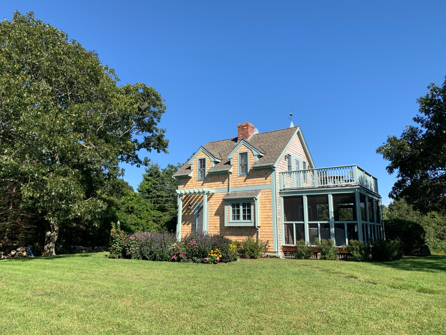 a view of a white house with a big yard and potted plants and big trees