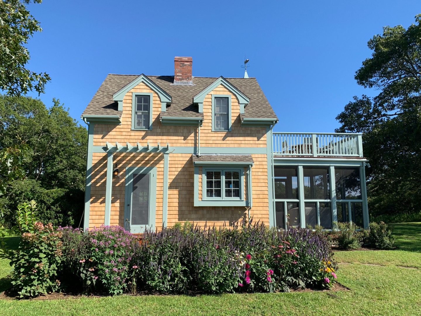 60 Meetinghouse Road Chilmark, MA 02535 - Photo 5 of 23 a view of a white house with large windows and a yard with plants and large trees