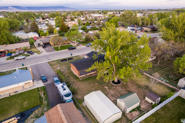 634 South 2100th Street West Vernal, UT 84078 - Photo 65 of 71 Expansive property featuring a mature shade tree, a brick and siding exterior, a dark shingled roof, and a large white vinyl fence
