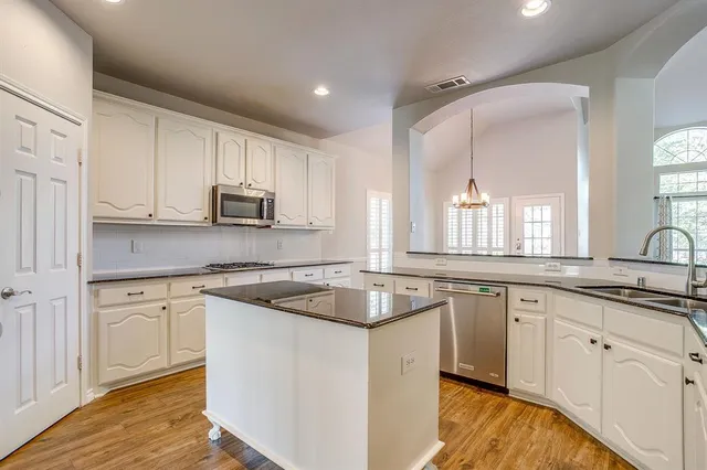 a kitchen with appliances a sink cabinets and wooden floor