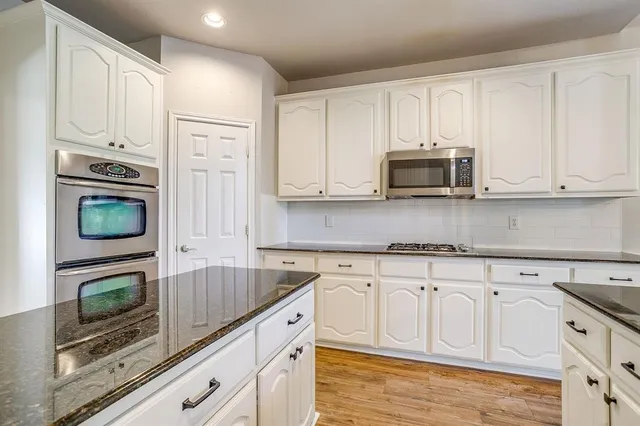 a kitchen with granite countertop white cabinets stainless steel appliances and a sink