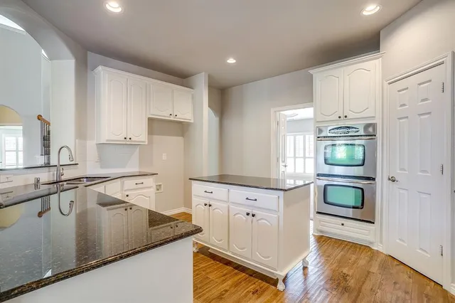 a kitchen with granite countertop a stove sink and cabinets