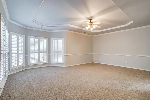 an empty room with chandelier fan and windows