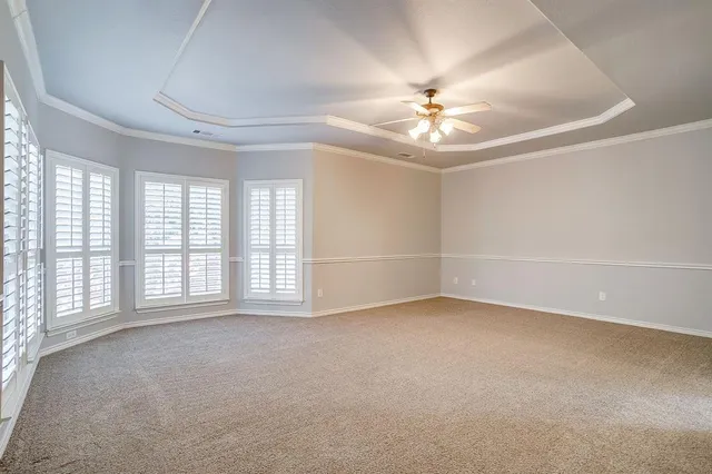 an empty room with chandelier fan and windows