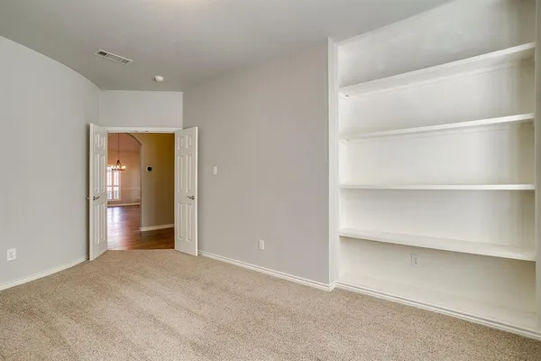 a view of an empty room with a cabinet and mirror