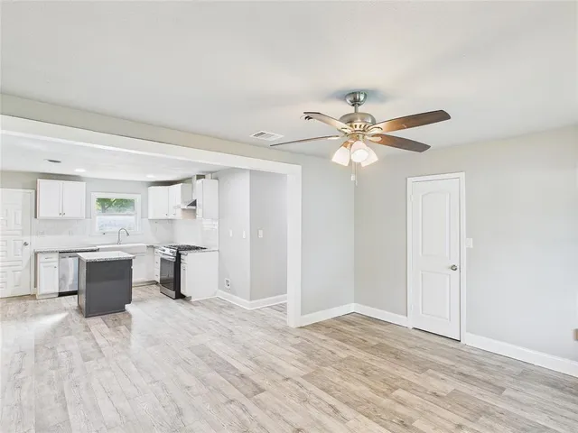 a view of a livingroom with a fireplace a ceiling fan and wooden floor