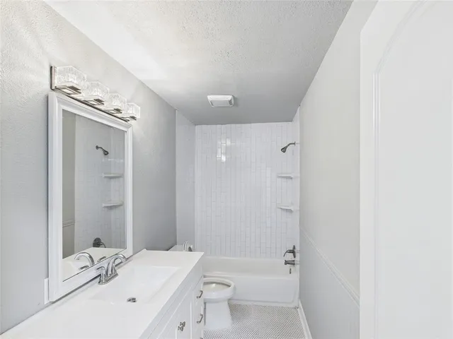 a bathroom with a bathtub shower sink vanity and toilet
