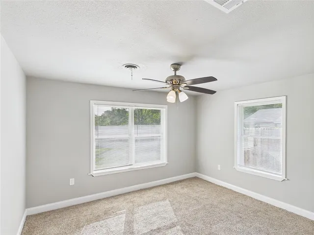 an empty room with windows and fan