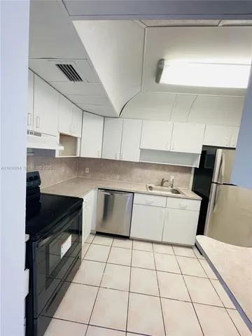 a kitchen with a sink a stove top oven and white cabinets
