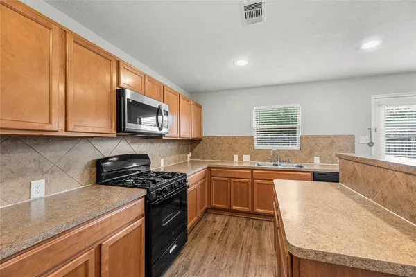 a kitchen with stainless steel appliances refrigerator cabinets and wooden floor