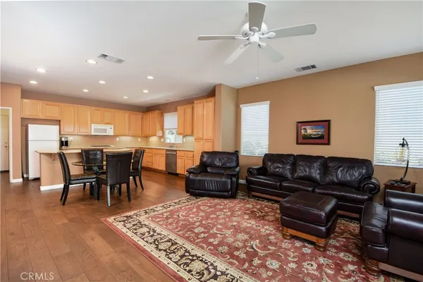 a living room with furniture kitchen view and a wooden floor