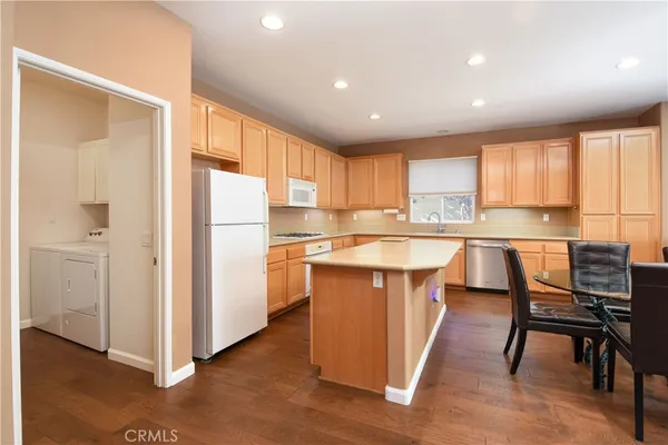 a kitchen with stainless steel appliances granite countertop a refrigerator a sink dishwasher and a stove with wooden floor