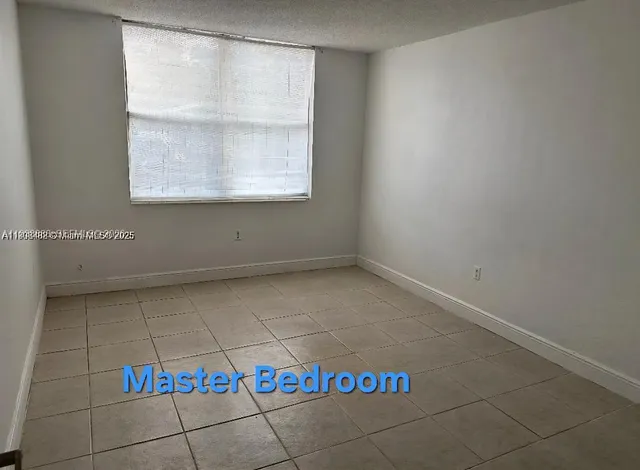 a large white kitchen with cabinets and a view of living room