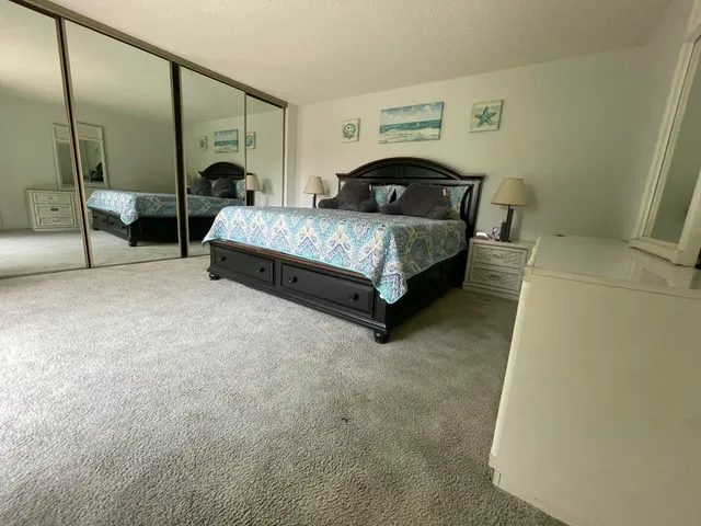 a bedroom with a bed table and a mirror