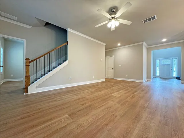 a view of an empty room and chandelier fan and wooden floor