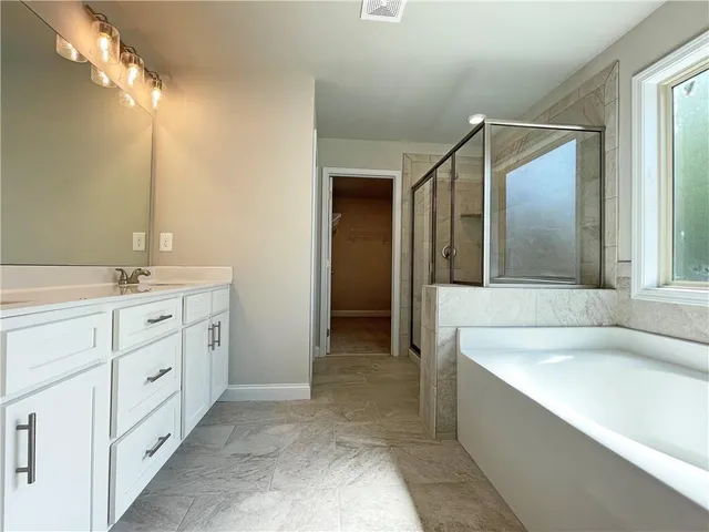 a spacious bathroom with a tub sink and mirror