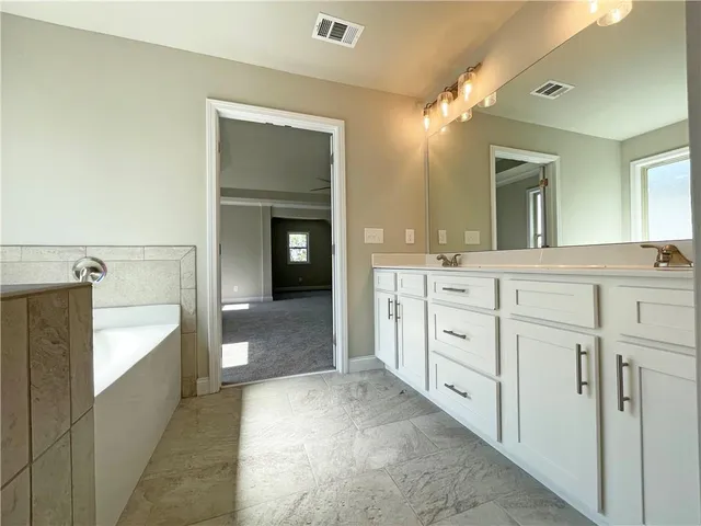 a spacious bathroom with a granite countertop sink mirror and bathtub