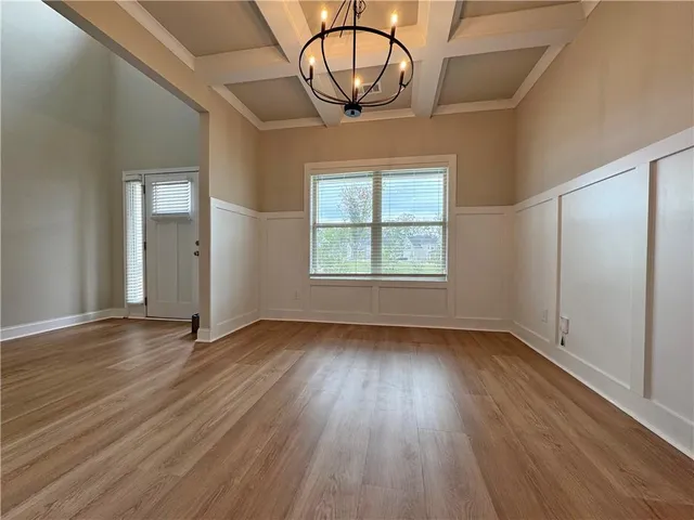 an empty room with wooden floor a ceiling fan and windows