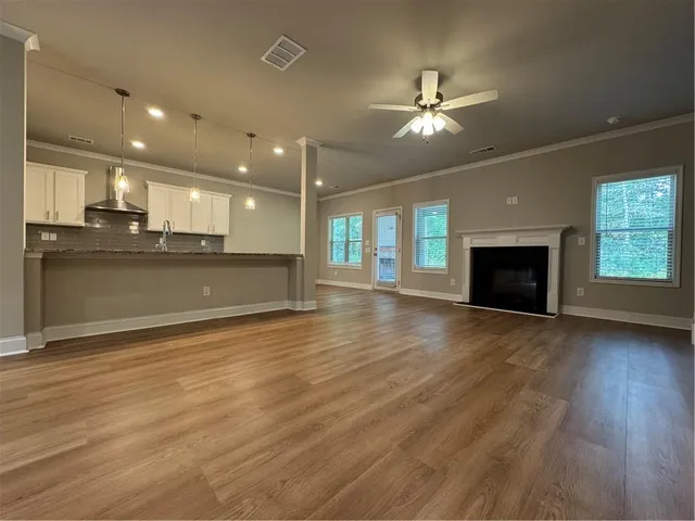 an empty room with wooden floor fireplace and windows