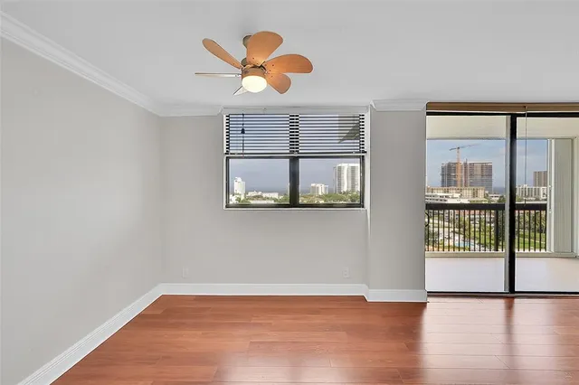 a view of an empty room with wooden floor and a window