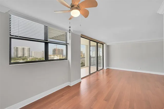 a view of an empty room with wooden floor and a window