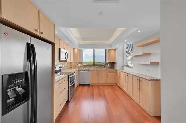a kitchen with granite countertop stainless steel appliances a sink cabinets and a window