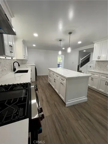 a large white kitchen with kitchen island a sink wooden floor and a refrigerator