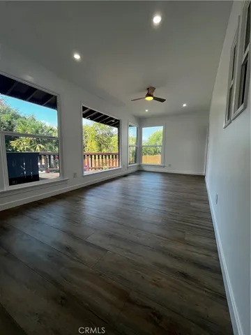 an empty room with wooden floor fireplace and windows