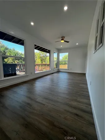 an empty room with wooden floor fireplace and windows