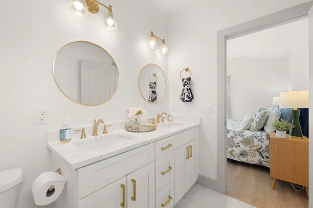 a bathroom with a double vanity sink toilet and a mirror