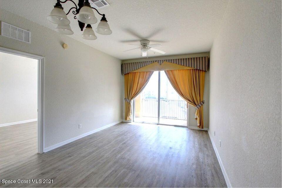 3848 Lexmark Lane, Unit 302 Rockledge, FL 32955 - Photo 5 of 18 an empty room with wooden floor fan and windows