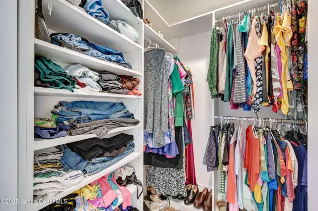 a view of walk in closet with clothes and shoes
